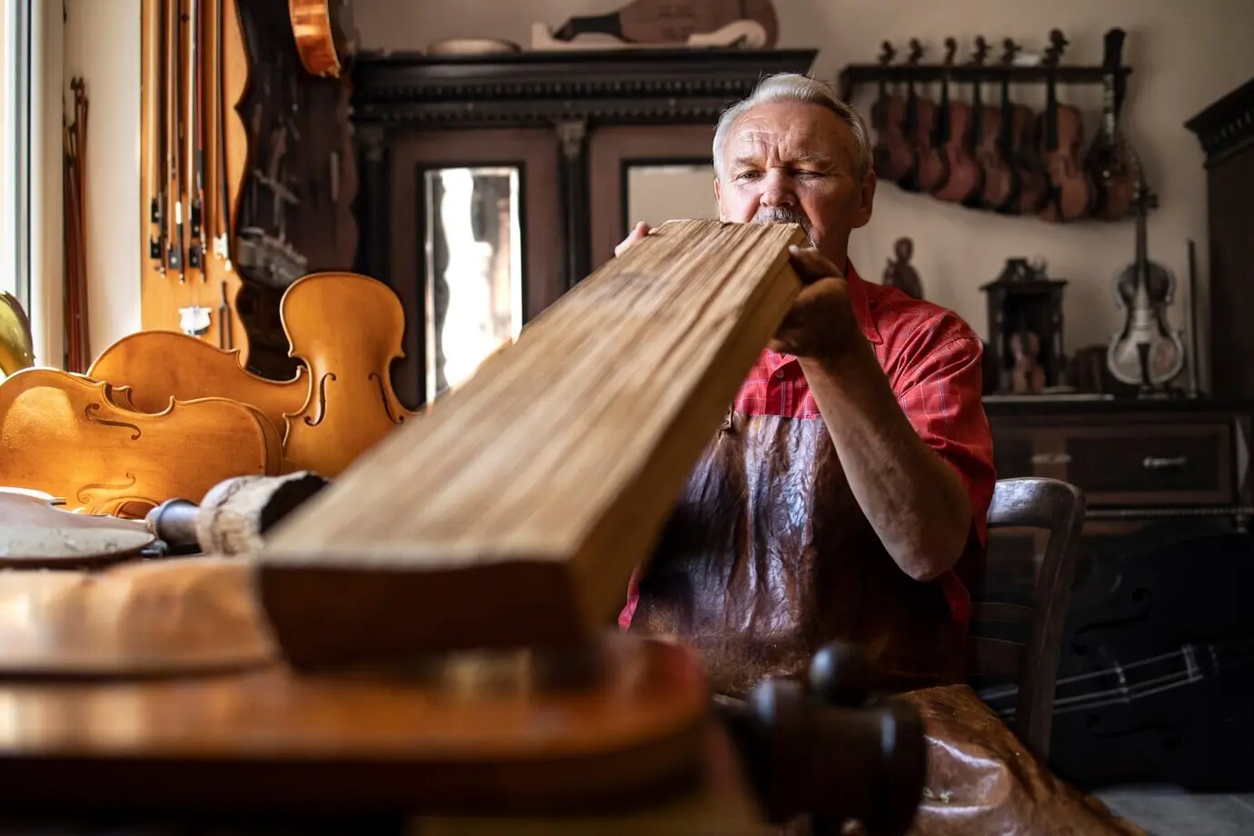 Senior carpenter craftsman inspecting the quality of a wooden plank before starting work.