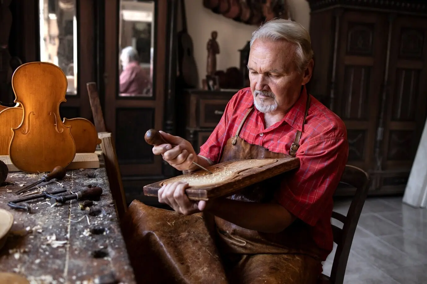 A focused senior carpenter calmly working on a new project in his old-fashioned workshop.