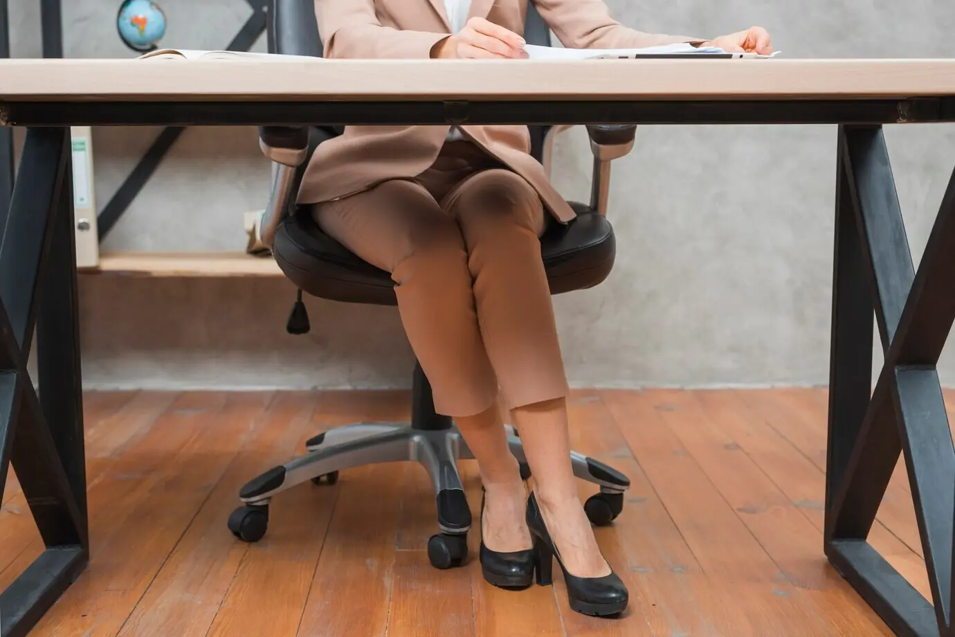 Lower body of a businesswoman seated on a chair in the workplace.